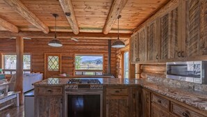 Une cuisine rustique avec des meubles en bois, un plan de travail en granit, un four encastré et un four à micro-ondes.