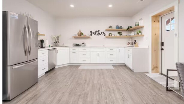 Eine moderne Küche mit weißen Schränken, einem Edelstahl-Kühlschrank und einem Schild mit der Aufschrift 'jather'.