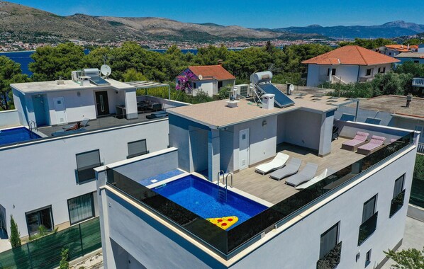 Une terrasse sur le toit avec une piscine, des chaises longues et une vue sur le paysage environnant.
