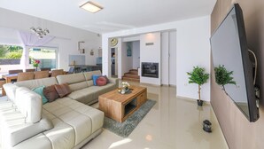 Una sala de estar moderna con un sofá seccional, una mesa de centro de madera y un televisor montado en la pared.