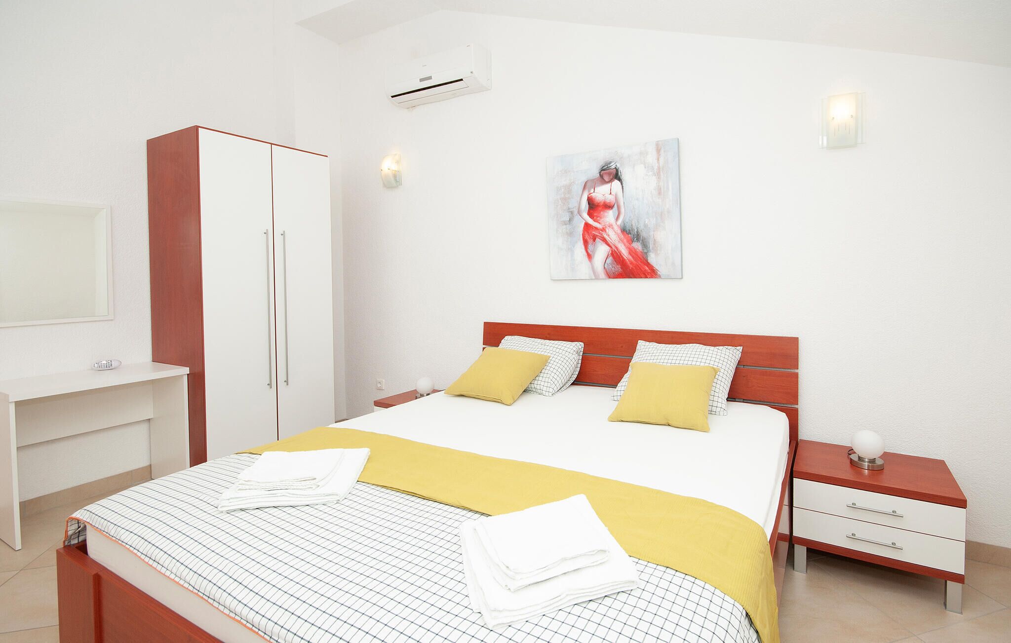 A bedroom with a bed, bedside tables, a wardrobe, and a painting on the wall.