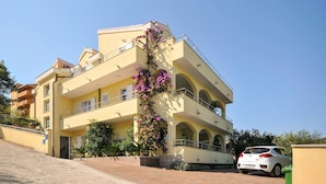 A multi-story building with balconies, a car parked in front, and a clear sky. - Gorgeous apartment in Okrug Gornji with house sea view (Okrug Gornji)