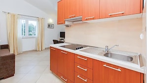 A kitchen with wooden cabinets, a sink, and a window with curtains. - Gorgeous apartment in Okrug Gornji with house sea view (Okrug Gornji)