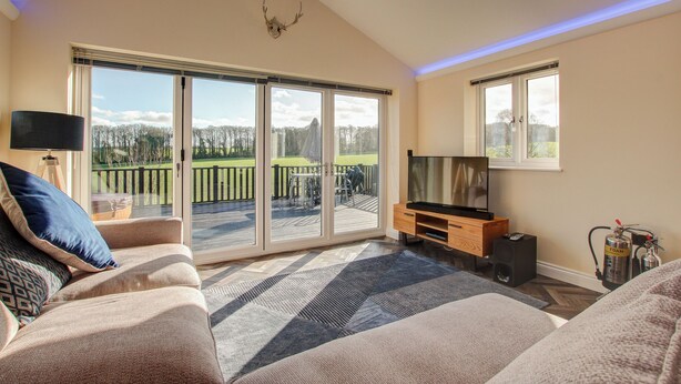 A living room with a sofa, TV, and a fireplace. - Hunters Cottage – A Romantic Luxury Retreat with Hot Tub & Slipper Bath, AC (Blandford Forum)