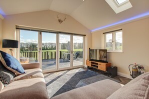 A living room with a sofa, TV, and a fireplace. - Hunters Cottage – A Romantic Luxury Retreat with Hot Tub & Slipper Bath, AC (Blandford Forum)