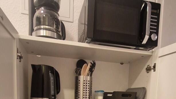 A kitchen with a coffee maker, microwave, toaster, and various pots and pans. - Cozy 1-room apartment in the Hildesheim forest (Diekholzen)