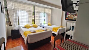 Une chambre d’hôtel avec deux lits, une télévision et une fenêtre avec des rideaux.
