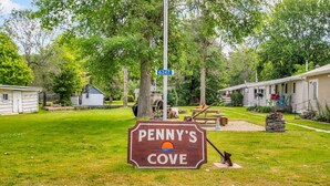 Penny's Cove, eine Wiese, eine hölzerne Bank und ein Werbeschild.