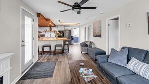Ein geräumiger Wohnbereich mit grauem Sofa, einem Couchtisch und einem Deckenventilator.