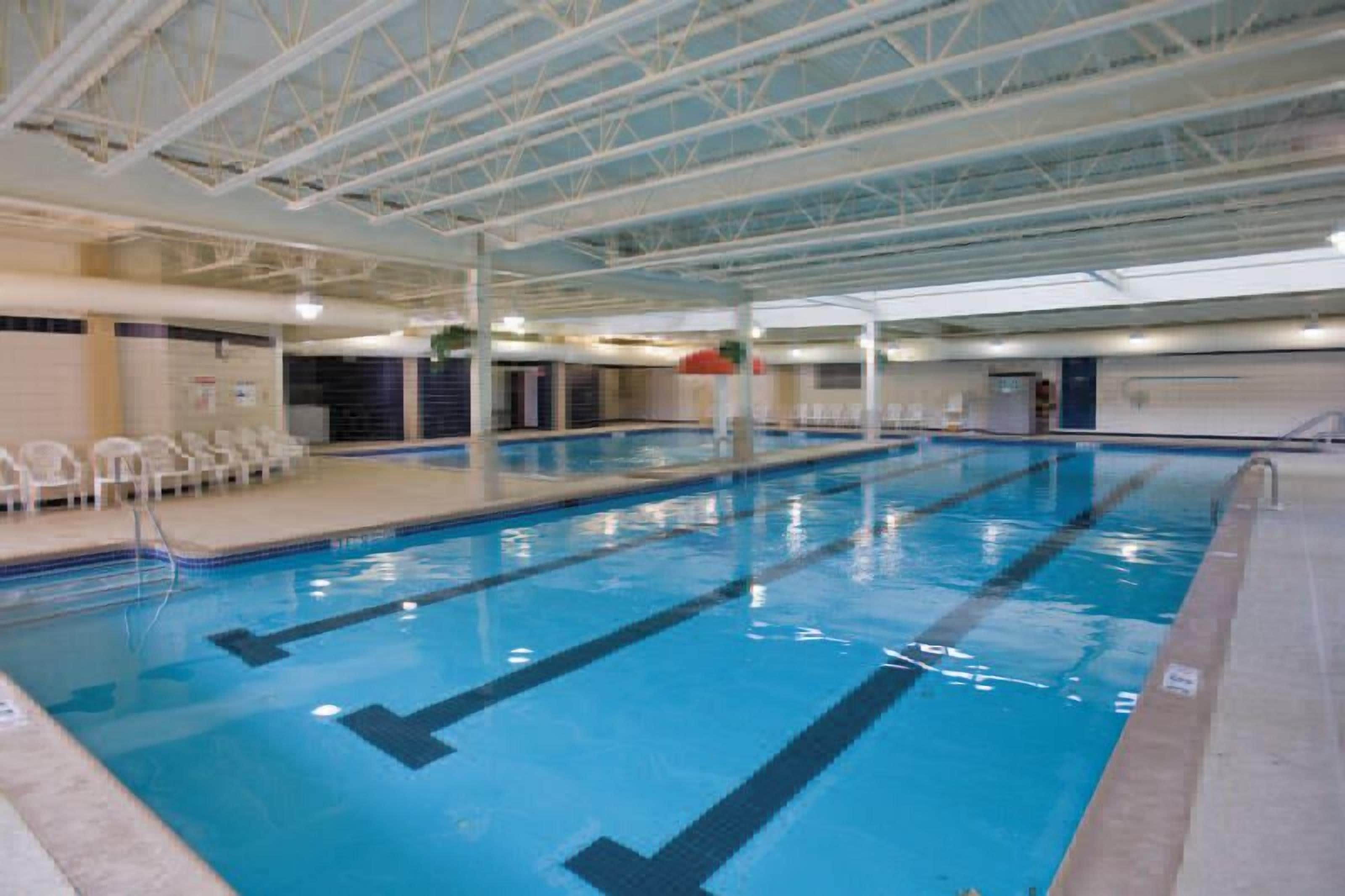 En inomhuspool med banor, en åskådarplats och en täckt takkonstruktion.