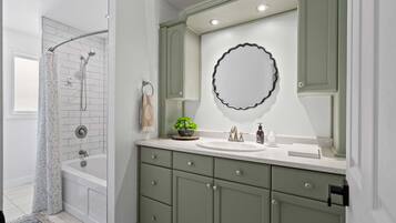 A bathroom with a bathtub, a shower, a sink, and a vanity with drawers.