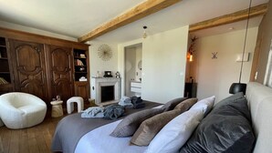 Ein Schlafzimmer mit einem großen Bett, einem Holzschrank, einem kleinen Nachttisch und einem Kamin.