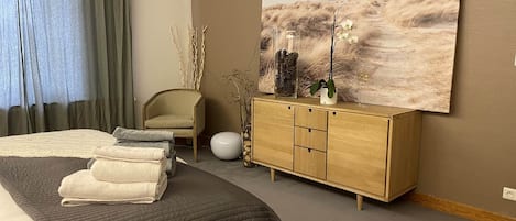 Une chambre à coucher moderne avec un grand lit, une commode en bois et un tableau accroché au mur.