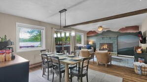 Un comedor con una mesa lista para cuatro personas, una chimenea y vistas al exterior.