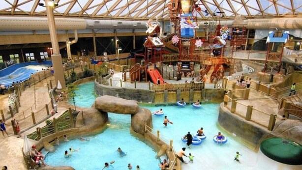 Parque acuático interior con múltiples piscinas y toboganes.