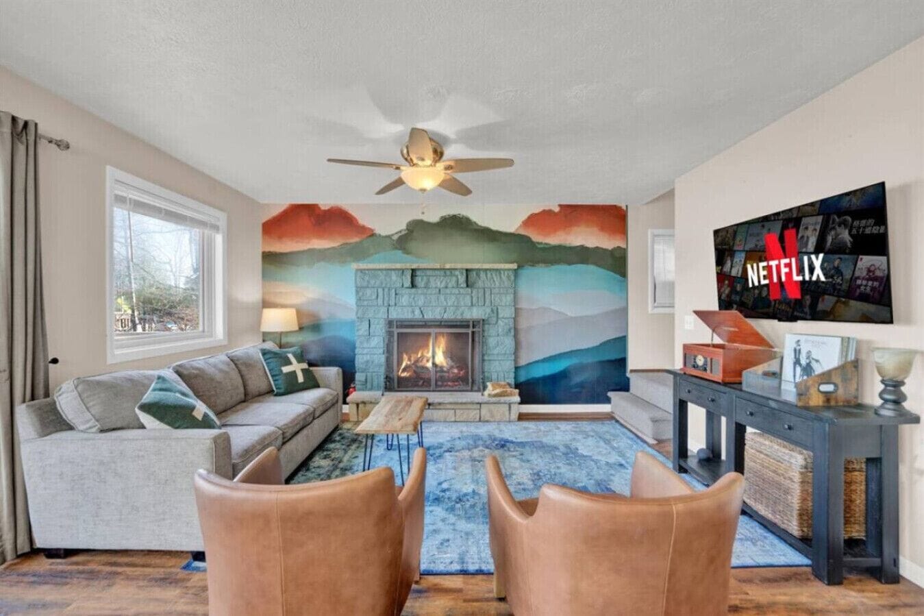 A living room with a fireplace, a sofa, a coffee table, and a TV mounted on the wall.