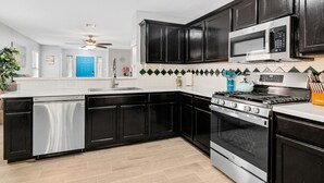 A modern kitchen with black cabinets, stainless steel appliances, and a tiled backsplash. - Quiet Austin Stay Near Tech (Austin)