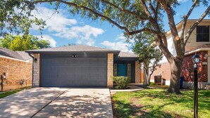 A residential garage with a brick exterior, a concrete driveway, and a tree in the foreground. - Quiet Austin Stay Near Tech (Austin)