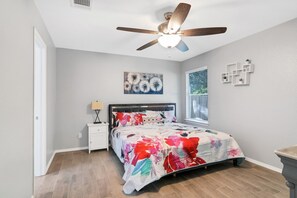 A bedroom with a bed, a nightstand, a ceiling fan, a window, and a wall with a painting. - Quiet Austin Stay Near Tech (Austin)