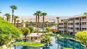 Un resort con edificios de varios pisos, un área de piscina central y vegetación circundante.