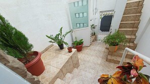 Un escalier agrémenté de plantes en pot, une porte avec des panneaux de verre et un sol carrelé.