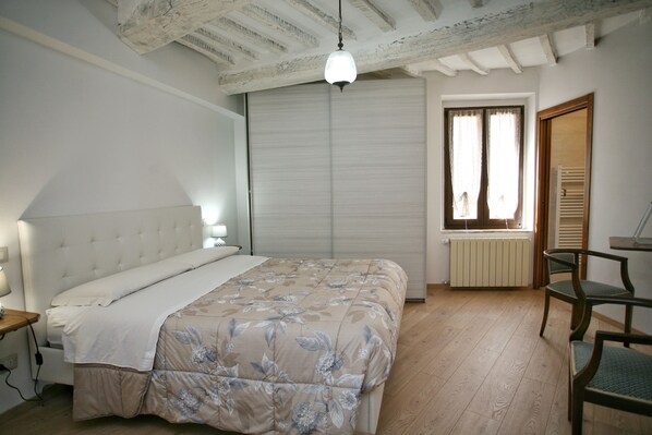 Een slaapkamer met een bed, een bureau en een stoel.