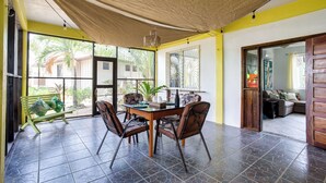 Un área de comedor con una mesa, sillas y un banco, con vistas al exterior.