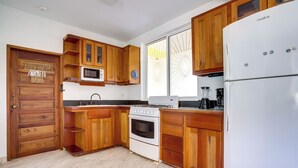 Una cocina con armarios de madera, un refrigerador blanco, una estufa y un microondas.