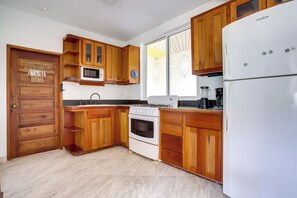 Eine Küche mit Holzausstattung, einem weißen Kühlschrank, einem Herd und einer Mikrowelle.