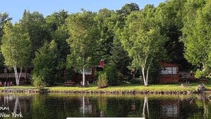 Järvenrantatontti, jolla on talo, ja sen ympärillä on tiheä puusto sekä rauhallinen vesialue.