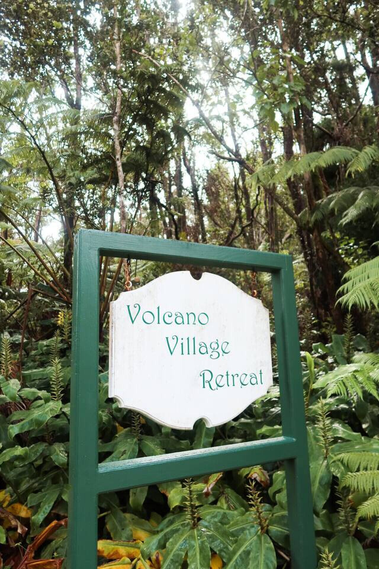 A sign for Volcano Village Retreat surrounded by lush greenery.