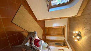 A cozy room with a wicker chair, a small table, a decorative wall light, and a wooden cabinet. - in ruhiger Lage nahe am See by Interhome (Thiersee)