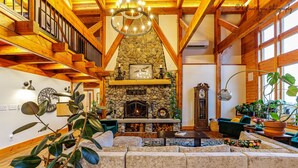 Una sala de estar acogedora con chimenea de piedra, vigas de madera y asientos cómodos.