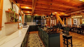 Una cocina amplia con una isla grande, vigas de techo de madera y electrodomésticos modernos.