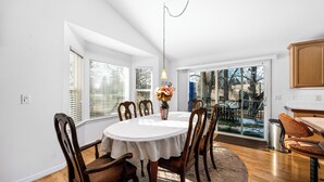 Un coin repas avec une table ronde, des chaises en bois et un vase de fleurs.