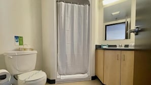 Une salle de bain avec des toilettes, un rideau de douche et des meubles en bois.