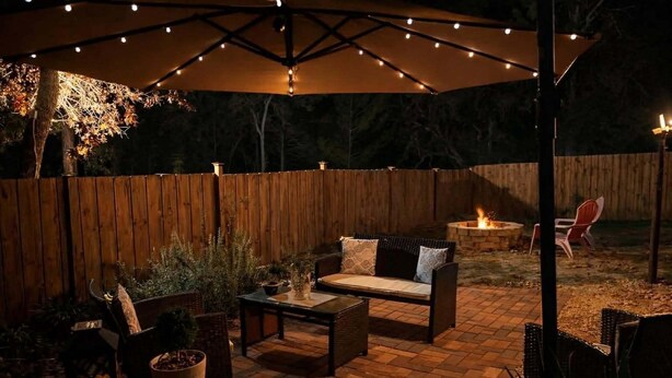 Een terras buiten met een houten omheining, een vuurkorf en tuinmeubilair.