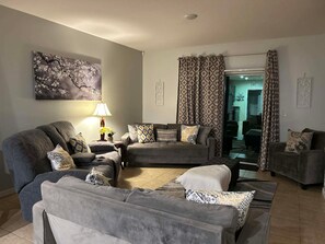 Un salon avec un ensemble de canapés, une lampe et un tableau accroché au mur.