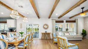 A spacious living area with wooden beams, a dining table set for six, and a sofa with cushions. - Isle of Palms: Sleeps 27, Lazy River & Waterslide (Indio)
