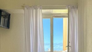 A bedroom with a bed, a TV mounted on the wall, and a balcony with curtains. - Hotel Costamar Miramar (Miramar)