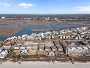 An aerial view of a coastal residential area with houses, a beach, and a large body of water. - Island Time Direct beach access, shared pool (Ocean Isle Beach)