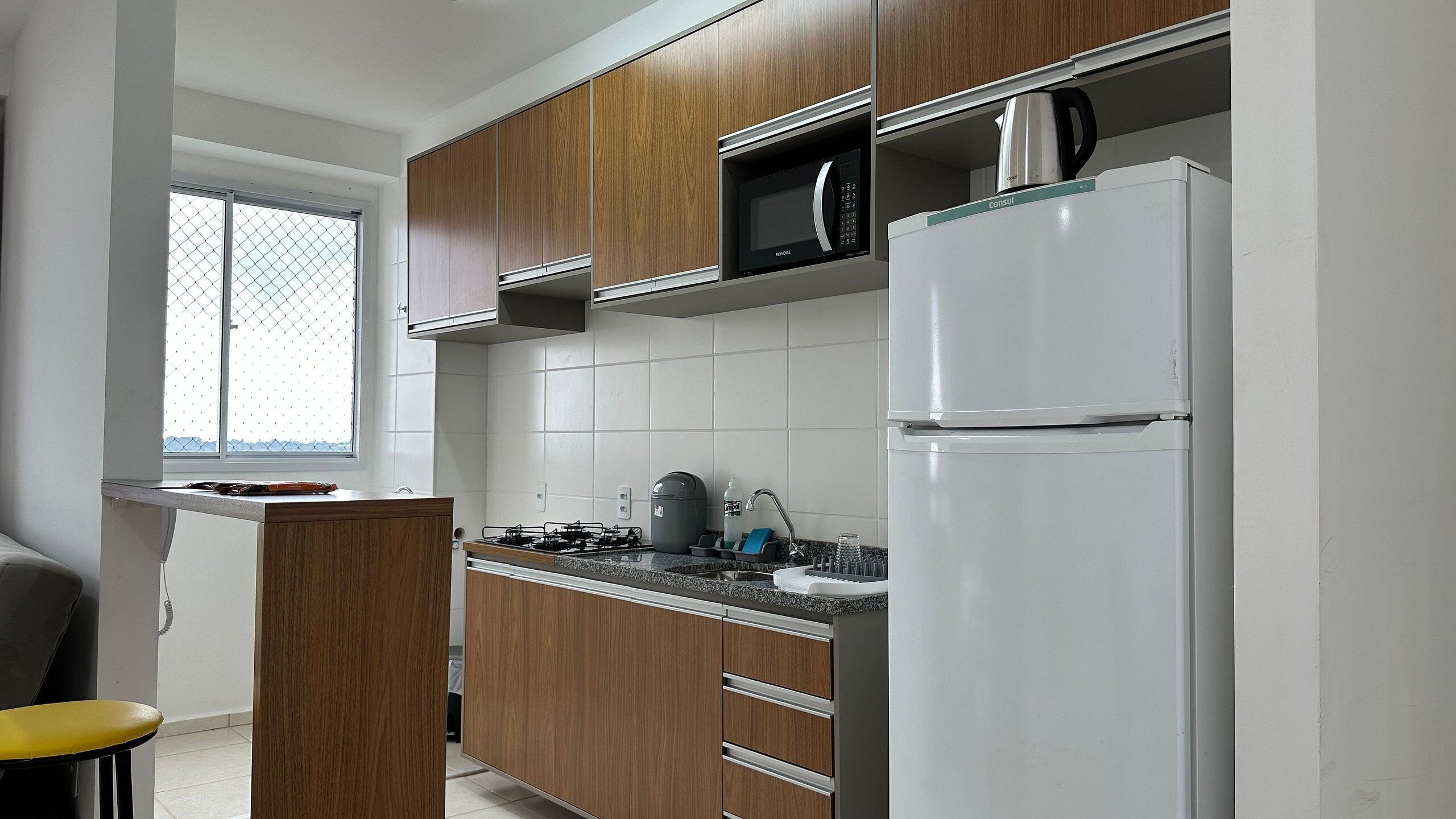 A kitchen with wooden cabinets, a microwave, a stove, and a refrigerator.