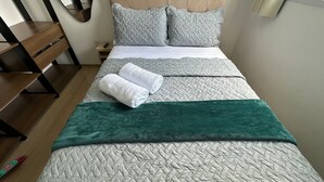 A bed with multiple blankets and pillows, a wooden nightstand, and a mirror on the wall. - Apto. 2 quartos Vista Rio Negro P. Negra (Manaus)