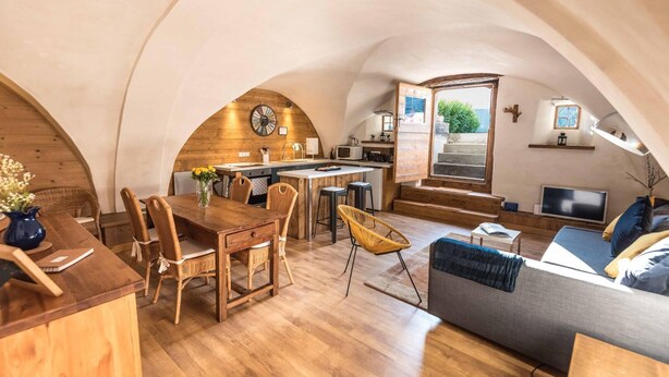 Um interior acolhedor com uma mesa de jantar de madeira, cadeiras, um sofá e uma televisão.