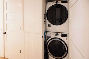 A laundry room with two stacked front-loading washing machines. - The Helène Estate - Spacious 3BD, 3.5BA - 2 Blocks from King St! (Charleston)