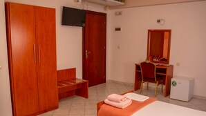 Une chambre comprenant un lit, un bureau, une chaise, une armoire et un petit réfrigérateur.