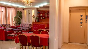 Une chambre d’hôtel dotée d’un coin repas avec des meubles rouges, un lustre et un minibar.