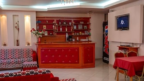 A hotel lobby with a red sofa set, a red bar area, a television, and a Pepsi vending machine. - Jayne s Rooms - Elassona Single Nest (Elassona)