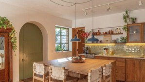 Une cuisine avec une table et des chaises en bois, une fenêtre et un mur recouvert de carreaux.