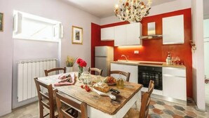 A modern kitchen with white cabinets, a red accent wall, and a chandelier. - Juniper Apartment - Relax, Nature and Panorama with Private Pool (Toscana)